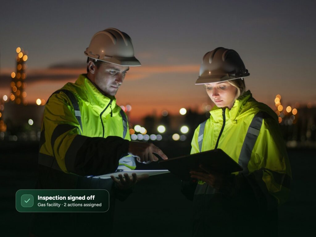 Two engineers reviewing a digital inspection on a tablet at an energy facility at dusk